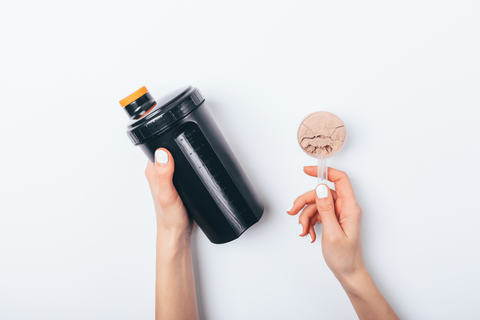 woman putting protein powder in shaker bottle